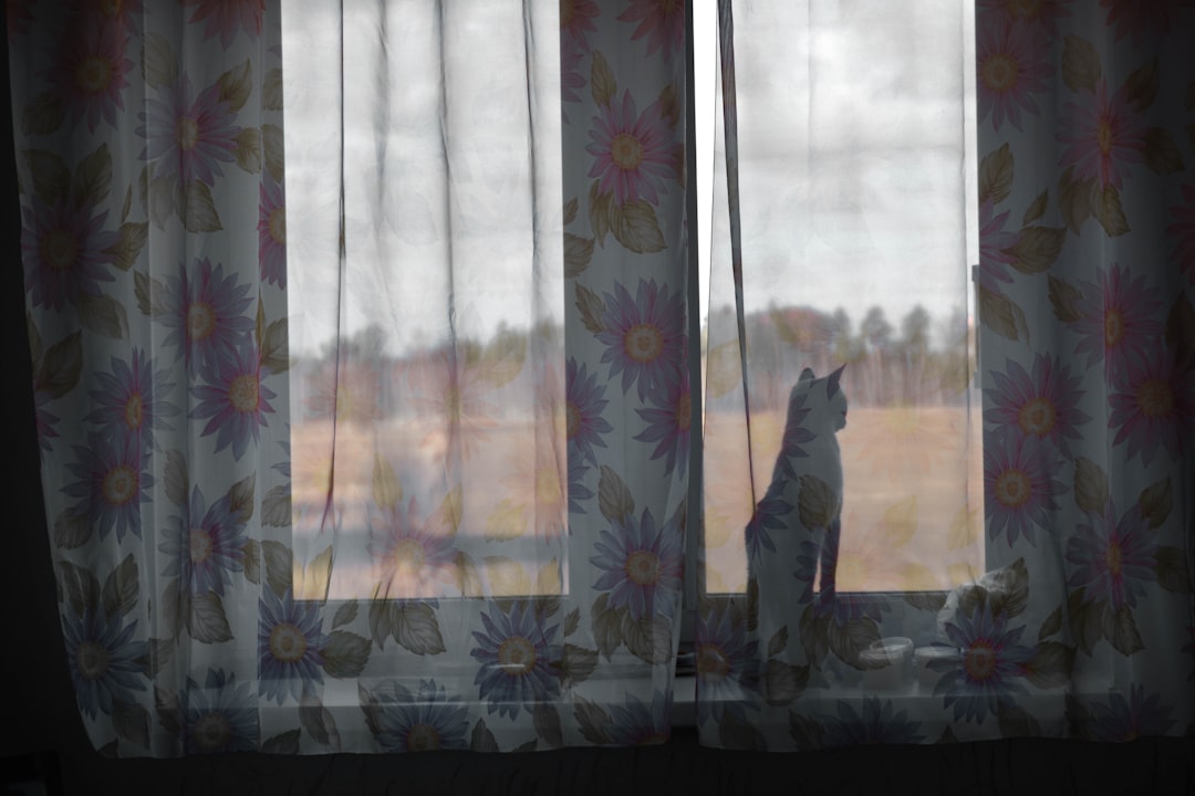 man in black jacket standing near white floral curtain